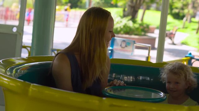 Woman and her kids enjoy riding an attraction of a tea cups spinning in a circle