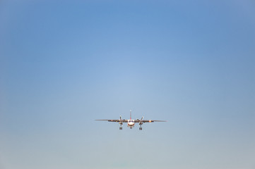 white airplane with screw engines with chassis released in the blue sky, front view