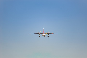 white airplane with screw engines with chassis released in the blue sky, front view