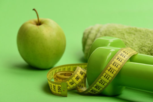 Dumbbells in bright green color, measure tape, towel and fruit