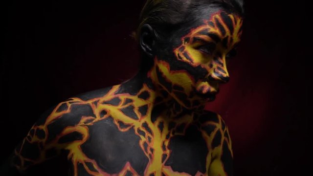 A girl with a bodypainting on her body in the image of a volcanic lava turns to her friend, slow motion