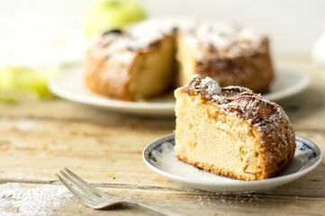 2. Piece of a freshly baked homemade apple pie with cake, fresh apple, silver fork and a powdered sugar on a side