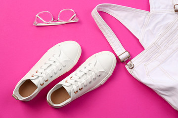 Comfortable casual female shoes, jumpsuit and glasses on color background