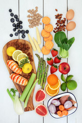 Health food for dieting concept with fresh seafood, fruit, vegetables, dairy, nuts and cereals. Super foods high in omega 3, antioxidants, fibre and vitamins. Top view on rustic wood background.
