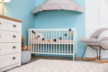 Modern interior of light cozy baby room with crib