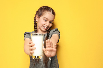 Little girl with dairy allergy holding glass of milk on color background