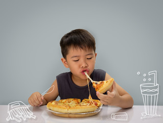 Asian 6-7 year boy is happy to eating pizza with a hot cheese with food draw on wall.