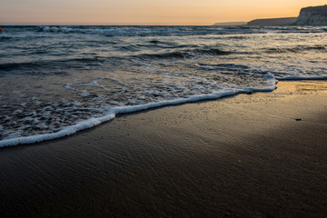 Waves approaching sandy beach during the sunset