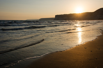 Waves approaching sandy beach during the sunset