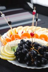 on a black background in a white plate fruit slicing, beautifully laid out
