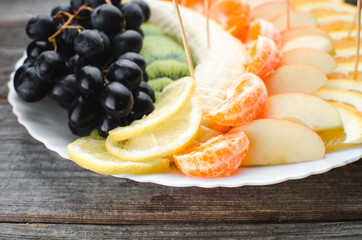 on a wooden background in a white plate fruit sliced, beautifully laid out