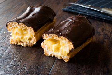 Half Cut Cream Filled Chocolate Eclairs on Dark Wooden Surface.