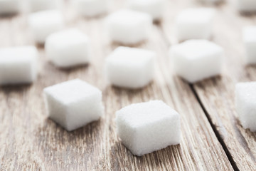 Cubes of white sugar on the wooden surface. Closeup, selective focus