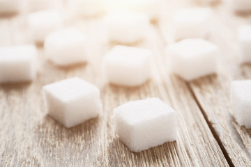 Fototapeta na wymiar Cubes of white sugar on the wooden surface. Closeup, selective focus, toned