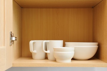 Different white dishes in cupboard in the kitchen. Scandinavian style.