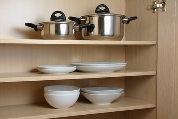 Different white dishes and pans in cupboard in the kitchen.Scandinavian style Concept order in the cupboard in the kitchen. 