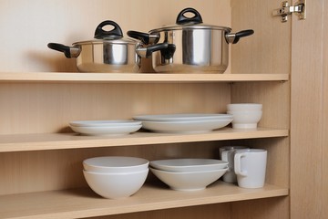 Different white dishes and pans in cupboard in the kitchen.Scandinavian style Concept order in the cupboard in the kitchen. 