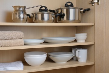 Naklejka na ściany i meble Different white dishes and pans in cupboard in the kitchen.Scandinavian style Concept order in the cupboard in the kitchen. 