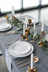 close up view of rustic table arrangement with eucalyptus, vintage cutlery, candles in candle holders and empty plates