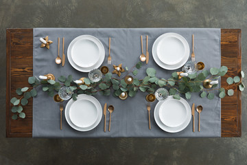 Top view of rustic table setting with eucalyptus, tarnished cutlery, wine glasses, candles and...