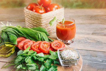 Tomato juice, a large branch of ripe red tomatoes on a wooden Board with leaves of ramsonand dill in a rustic style.