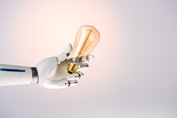 robot hand holding yellow lamp isolated on beige