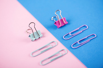 Clips of various colors on pink and blue background. Minimalist mockup.