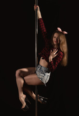 beautiful go-go dancer in denim shorts and checkered shirt in night club. Pole Dance pin-up girl