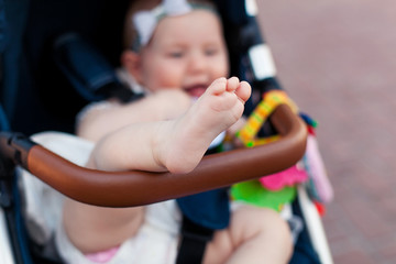 Newborn baby sleeping in stroller outdoors. Small baby barefoot with copy space. Selective focus