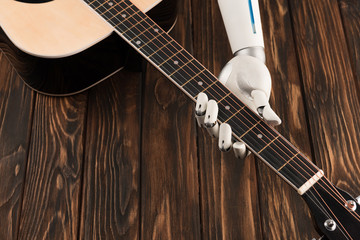 Fototapeta premium cropped shot of robot playing acoustic guitar over wooden surface