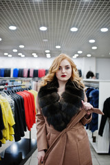 Elegance blonde girl in fur coat at the store of fur coats and leather jackets.