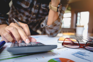 Close up of businessman or accountant working on calculator to calculate business data, and accountancy document. Business financial and accounting concept