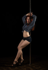 beautiful go-go dancer in denim shorts and checkered shirt in night club. Pole Dance pin-up girl
