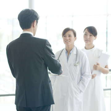 製薬会社の営業マンと話をする女医と看護師