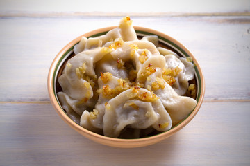 Pierogi or pyrohy, varenyky, vareniki, dumplings in bowl on wooden table. horizontal