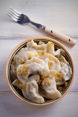 Pierogi or pyrohy, varenyky, vareniki, dumplings in bowl on wooden table. vertical