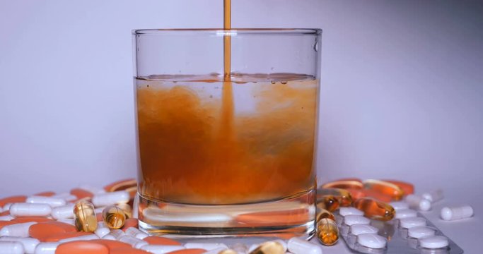 Crystal transparent glass with water and various tablets, syrup, white background.