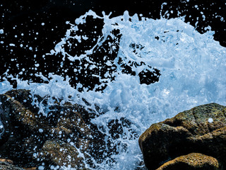 Sea water wave clashing rock amking white splash isolated on black background with clipping path