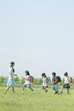 一列で歩く小学生と先生