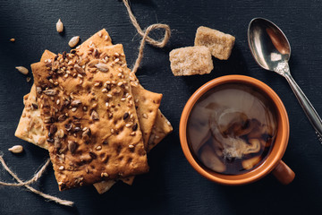 top view of cookies, cup of coffee, spoon and brown sugar on dark tabletop