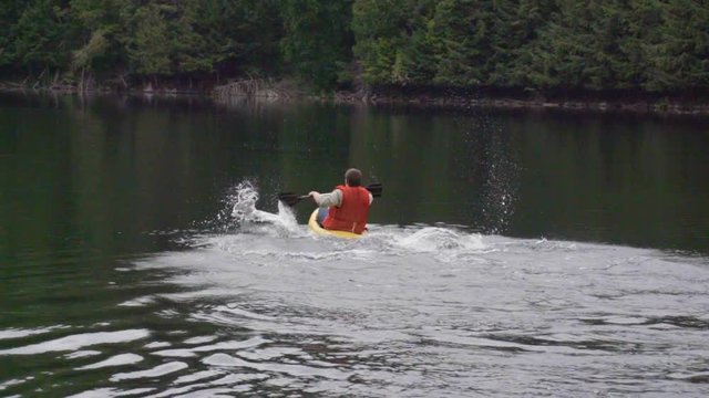 A man tips and falls out of his canoe while being filmed in slow motion.