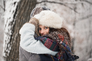 Side view of the happy young couple who is standing in the embrace in the snow-covered park