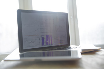 Close up of laptop with business chart on screen place on office desktop. Forex and finance concept