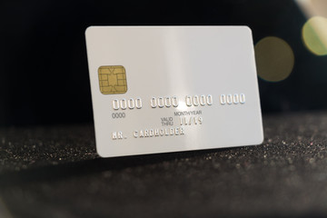 White blank credit card on dark background with bokeh