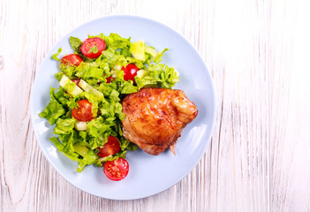 Roasted chicken thigh and salad on plate