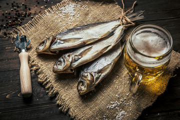 close-up dried fish, vintage glass of beer on a dark wooden background. Top view. Horizontal orientation.
