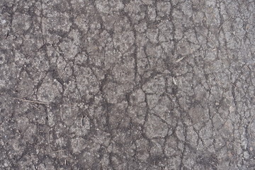 Fototapeta na wymiar Crackled surface of dusty old concrete road