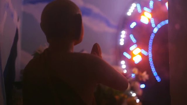 Buddha statue surrounded by flashing colorful festive lights on an abstract background in a Buddhist temple.