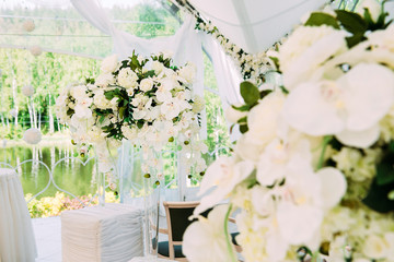 Wedding marquee with bouquets of roses. Beautiful wedding restaurant for marriage. White decor for bride and groom. Colorful decoration for celebration. Beauty bridal interior