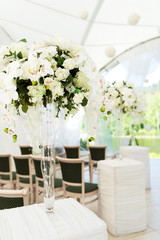 Beautifully decorated in white colours wedding hall. Wedding marquee with bouquets of roses